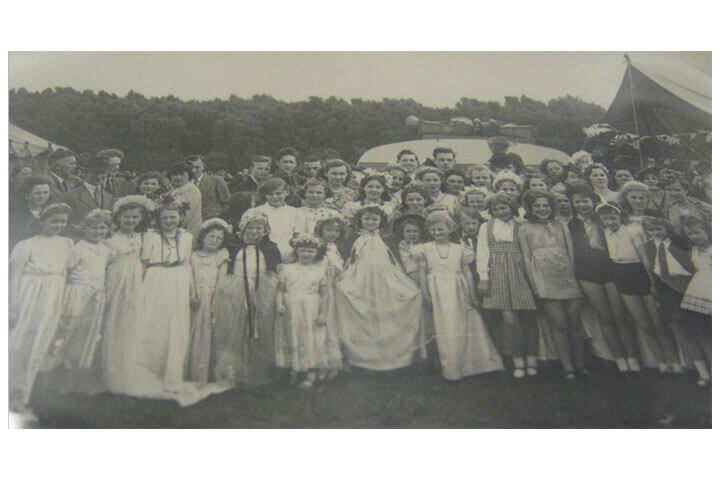 Black and white photo. Children and adults pose for a group photo.