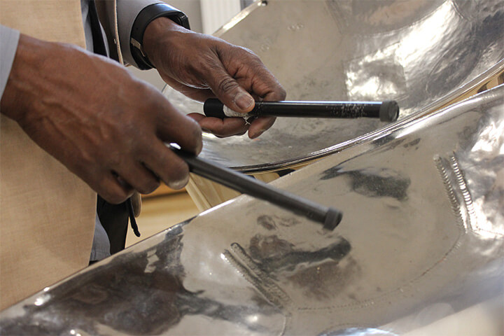 Close up photograph of hands playing steel drums.